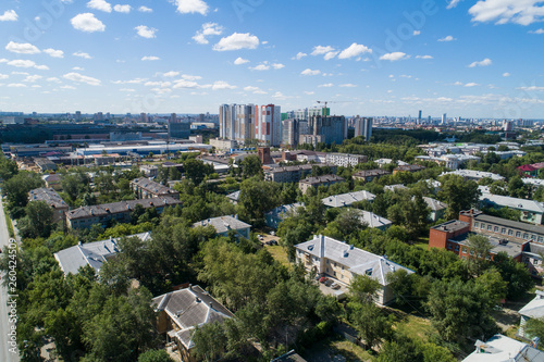 Top down aerial drone image of a Ekaterinburg with low houses and new high-rise buildings. Midst of summer, backyard turf grass and trees lush green.