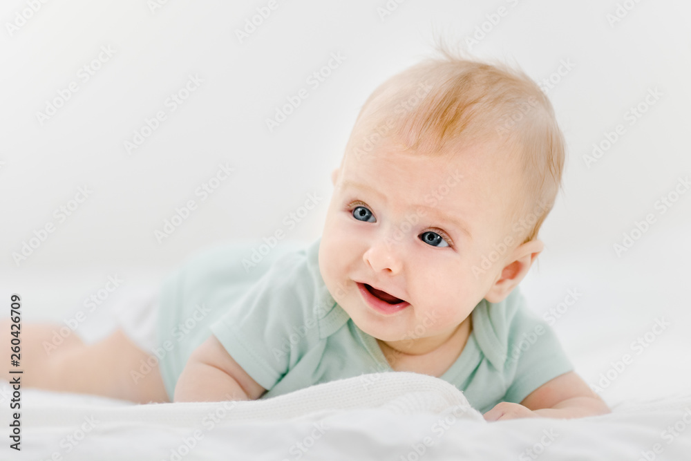 Portrait of beautiful infant baby lying on stomach in bed
