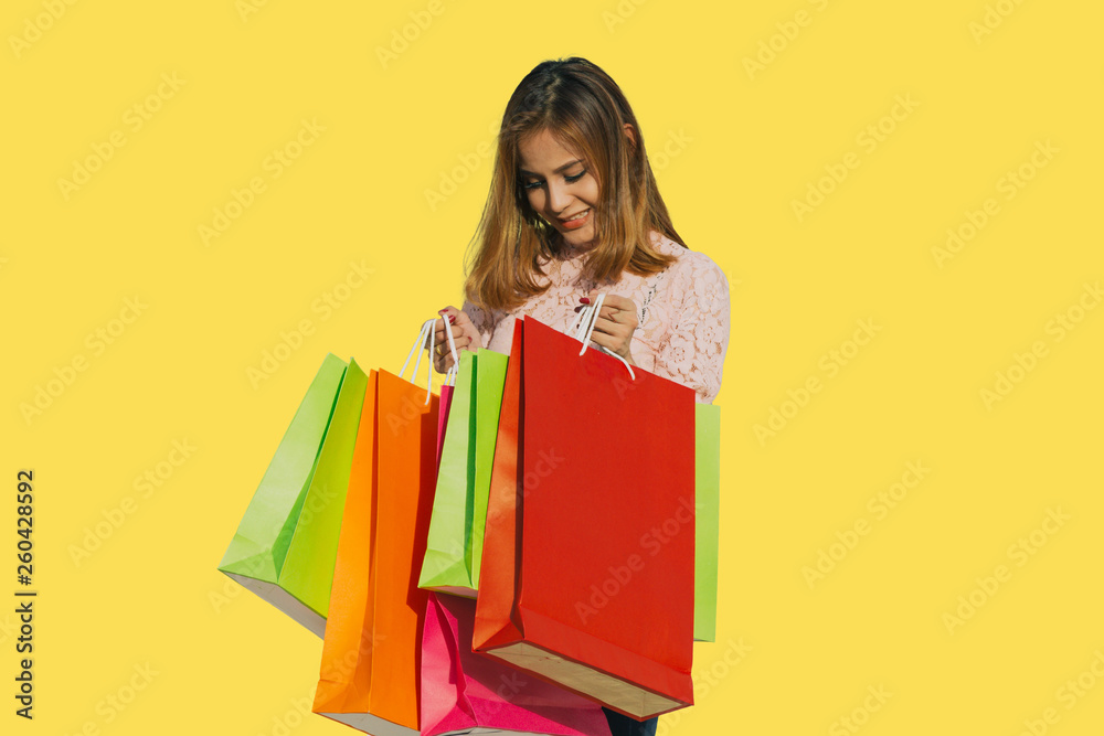 Asian women Beautiful girl is holding shopping bags and smiling on yellow background