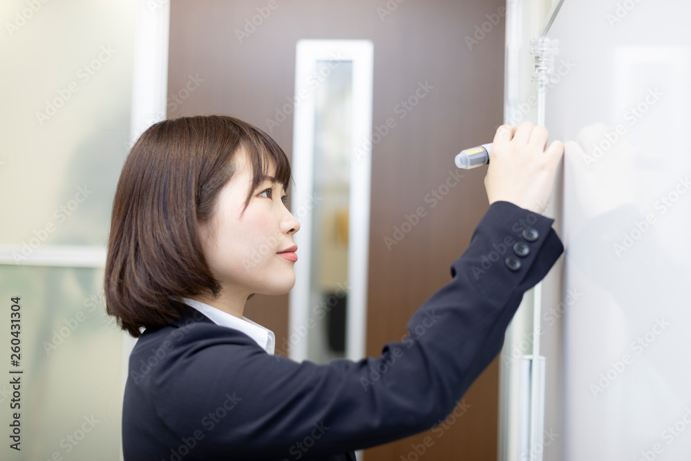 ホワイトボードに書き込むスーツの女性 ホワイトボードに書き込むスーツの女性