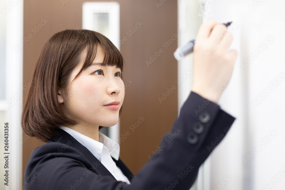 ホワイトボードに書き込むスーツの女性 ホワイトボードに書き込むスーツの女性