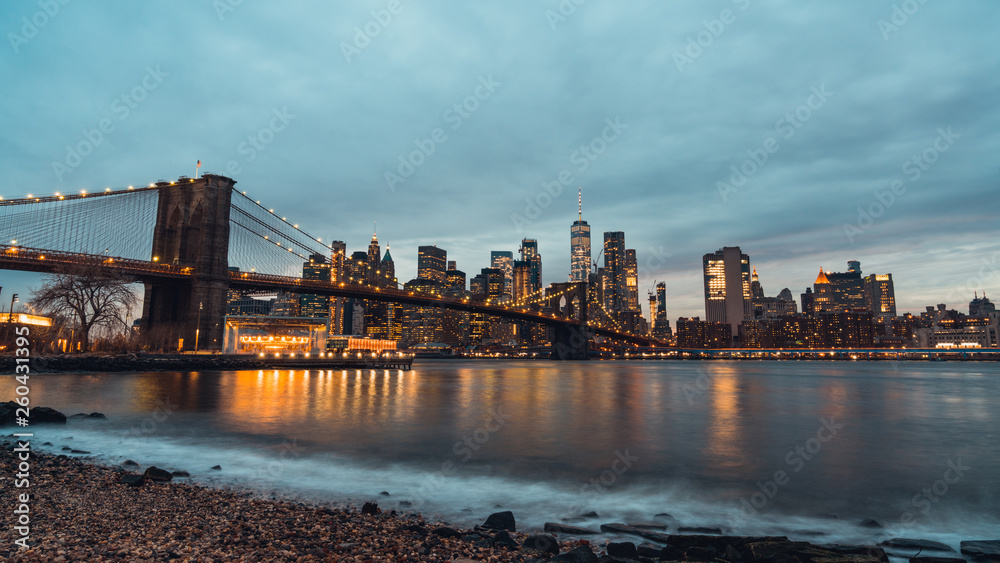 Fototapeta premium Cityscape night view of Brooklyn bridge and buildings in Manhattan New York City, United States. NYC business district, East America's landmark, USA tourist attraction, or travel destination concept