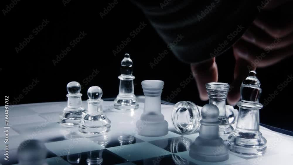 A chess match: a rook eating a king on a chessboard made of glass material. Angled close-up shot.