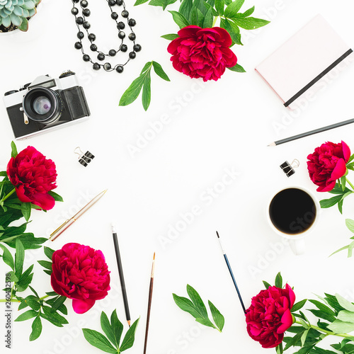 Frame composition. Blogger or freelancer workspace desk with retro camera, peonies and accessories on white background. Flat lay, top view.