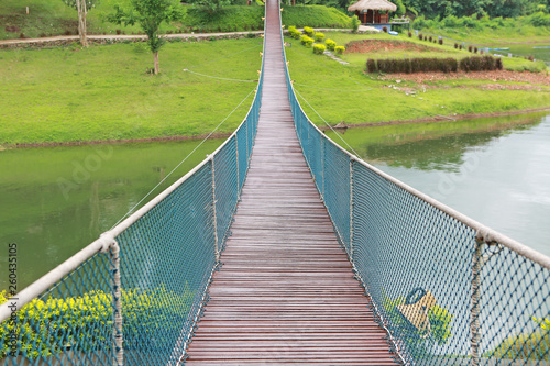 Fototapeta Naklejka Na Ścianę i Meble -  Perspective view of adventure wooden rope suspension bridge crossing river.