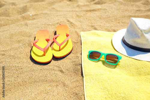 Flip flops near towel with hat and sunglasses