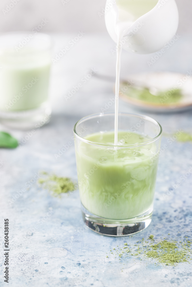 Iced Matcha green latte in glasses with matcha powder on light background. Iced Matcha green latte in glasses with matcha powder on light background.