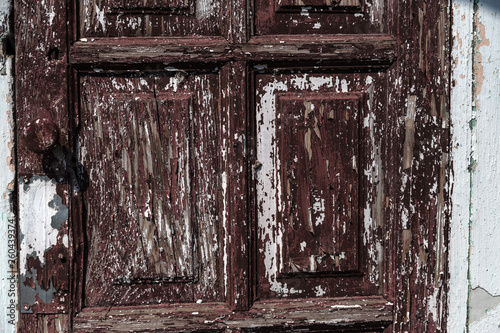 Fragment of an old wooden door, cracked paint on the tree. Wooden old cracked background. Vintage Shredded Cracked Exterior Door Wood