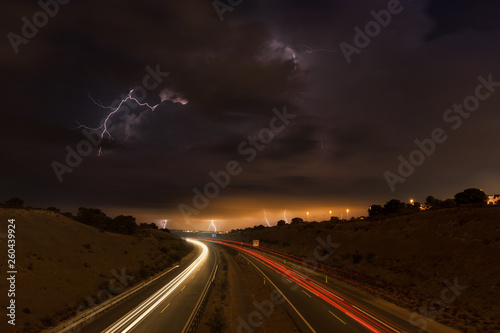 Ein Gewitter mit Blitzen und dramatischen Wolken in der Nacht über der Autobahn