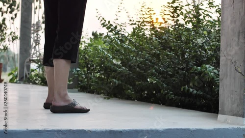 Asian Woman`s Legs in black Sandals and a Sweeping Broom in balcony photo