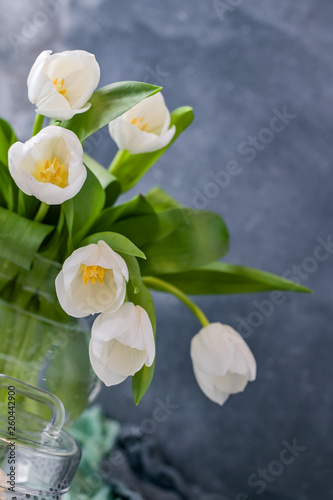 Fototapeta Naklejka Na Ścianę i Meble -  Bouquet of white tulips in a vase on a gray background. Flowers as a gift for your favorite person. Copy spce.
