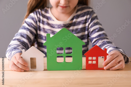 Little girl with models of house sitting at table. Concept of earthquake