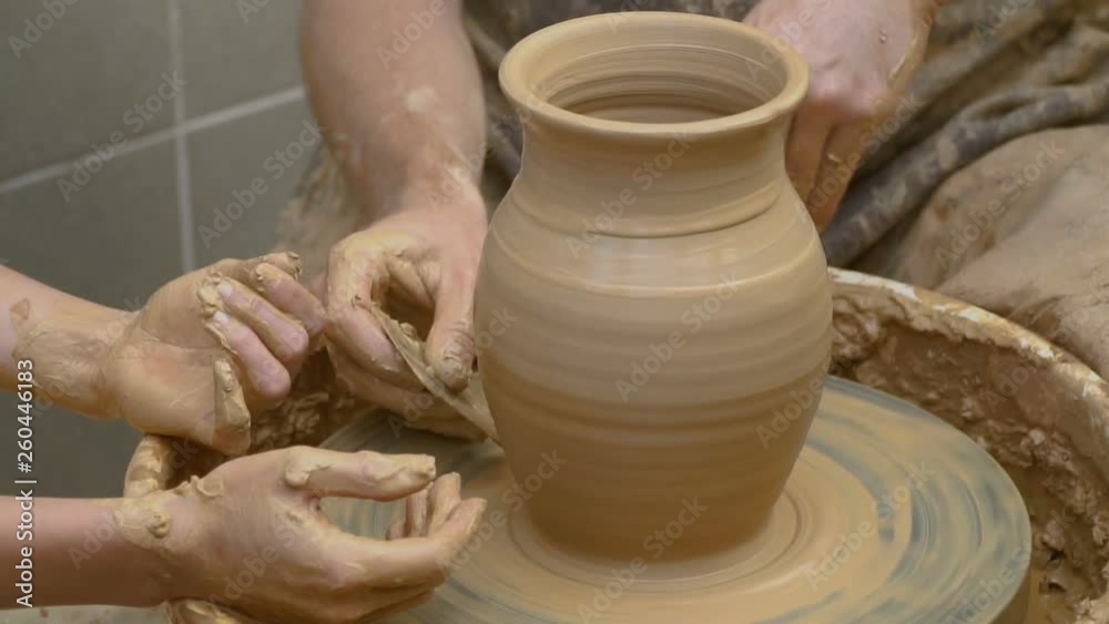 Two intertwined hands form a pot of clay on a potter's wheel. A male hand helps a woman's hands shape a clay shape. Two intertwined hands form a pot of clay on a potter's wheel. A male hand helps a woman's hands shape a clay shape.