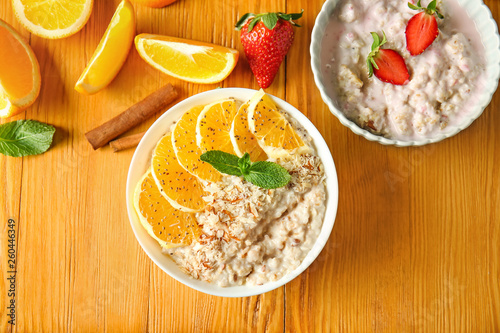 Bowls with tasty sweet oatmeal on wooden table