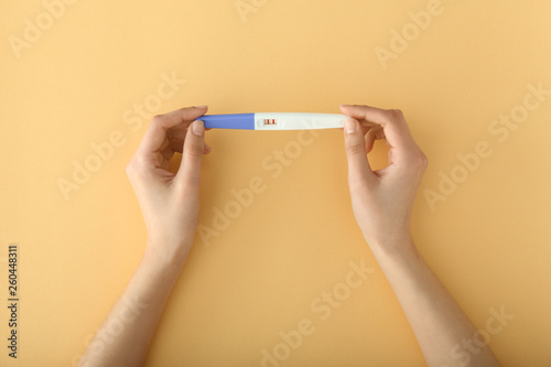 Female hands with pregnancy test on color background