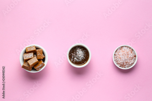 Tasty candies with caramel and salt on color background
