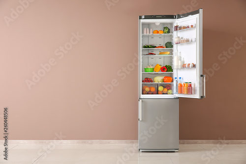 Open fridge full of food near color wall photo