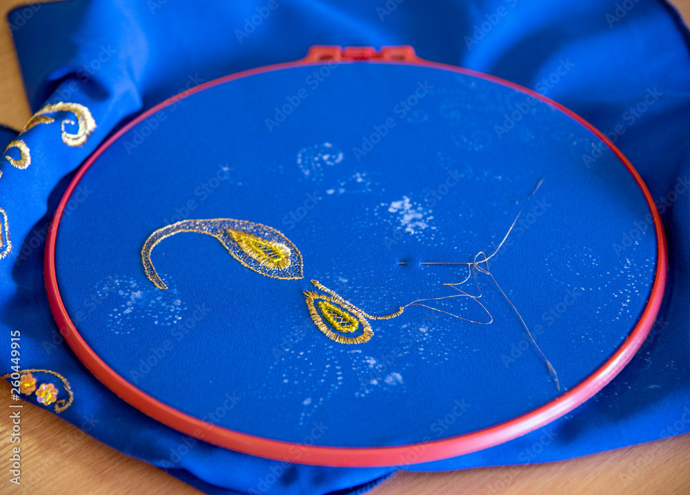 Fototapeta premium Master class on embroidery.The patterned gold thread on a blue background.