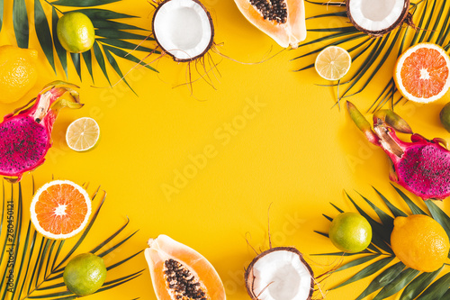 Fruits and palm leaves on yellow background. Citrus fruits. Summer concept. Flat lay, top view