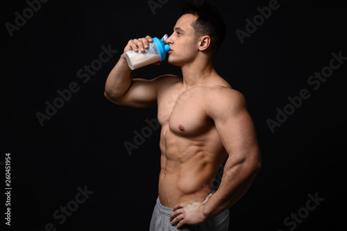 Sporty man with protein shake on dark background