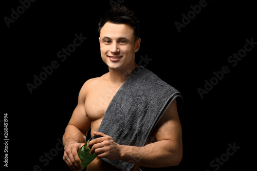 Sporty man with bottle of water on dark background © Pixel-Shot