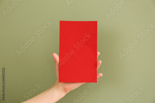 Female hand with blank invitation card on color background