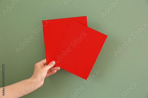 Female hand with blank invitation cards on color background