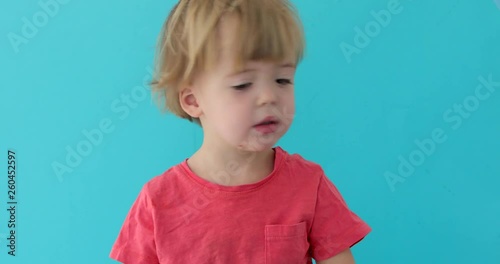 Serioius little blonde boy waving her head and saying no. Concept of a disagreement. Handheld studio shot photo