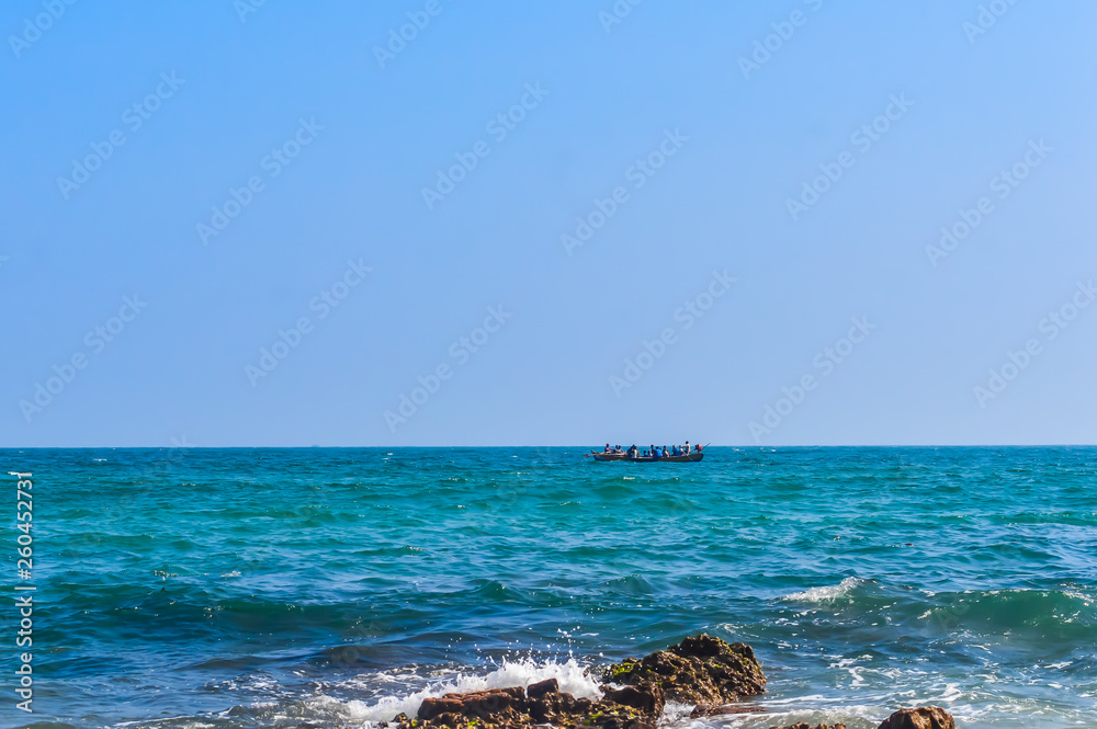silhouette of people on small wooden rowing boat on the sea with blue sky and waves during sunset. Chilika lake Bay of bengal, State of Odisha, India. Travel holiday vacation concept. Copy space room. silhouette of people on small wooden rowing boat on the sea with blue sky and waves during sunset. Chilika lake Bay of bengal, State of Odisha, India. Travel holiday vacation concept. Copy space room.