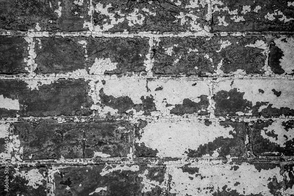 Rusty brick wall in black and white. Empty and rusty old brick wall texture. Distressed wall surface. Grunge stonewall background with peeling paint.