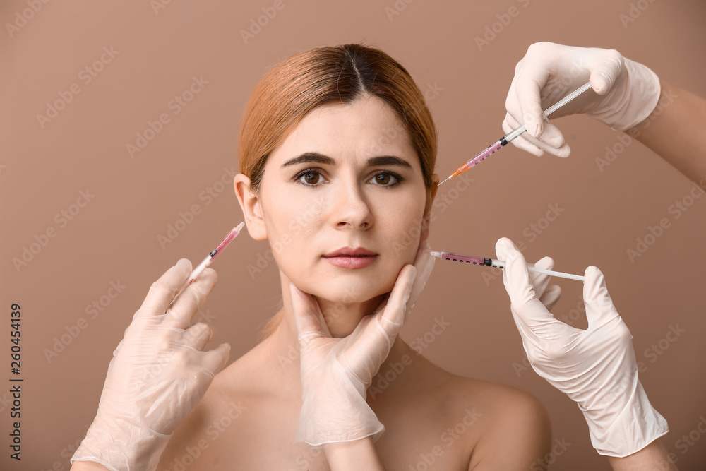 Obraz premium Beautiful woman and hands holding syringes for anti-aging injections on color background