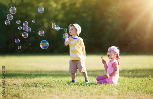 Happy children having fun in grass on sunny summer evening