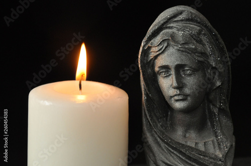 The Blessed Virgin Mary and a burning candle on a black background.