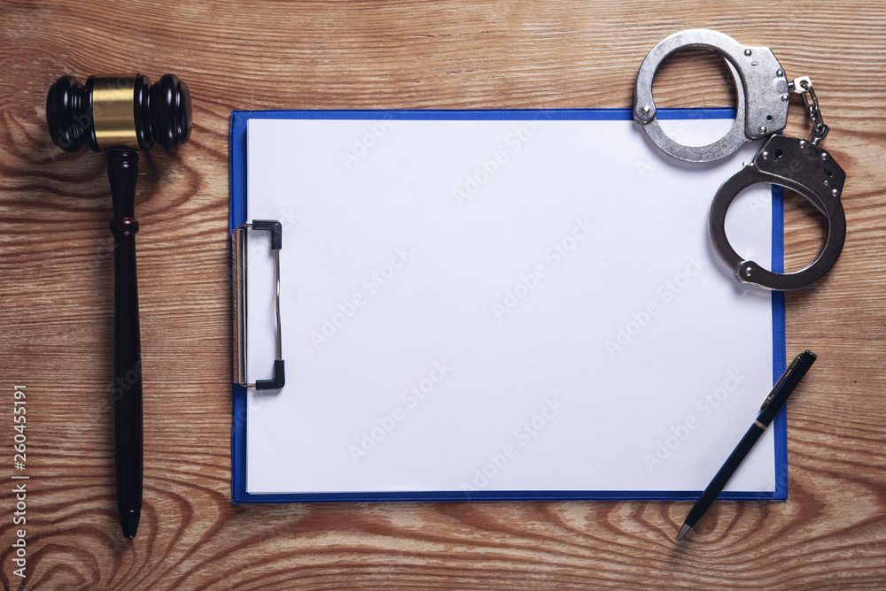 Clipboard, handcuffs, pen with judge gavel on wooden background. Clipboard, handcuffs, pen with judge gavel on wooden background.