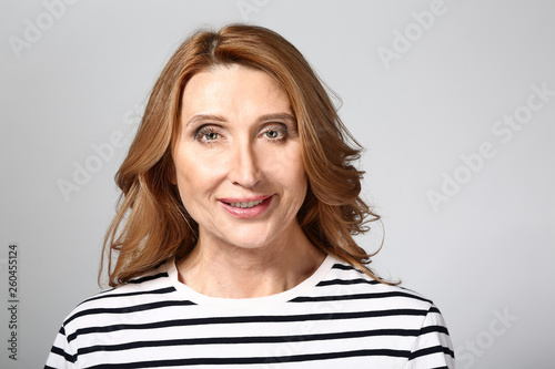 Stylish mature woman on grey background © Pixel-Shot