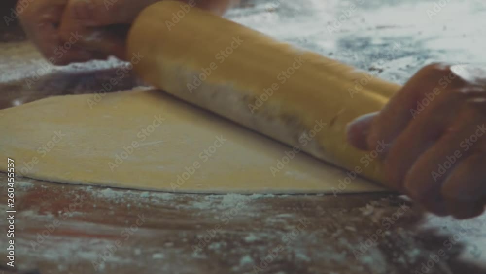 Female Hands Rolling Raw Dough Using a Rolling Pin at Bakery. Close Up View Female Hands Rolling Raw Dough Using a Rolling Pin at Bakery. Close Up View