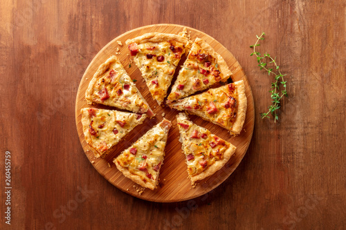 A quiche lorraine with thyme, shot from above on a dark rustic wooden background with copy space