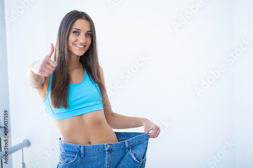Diet. Woman shows her weight loss and wearing her old jeans © Maksymiv Iurii