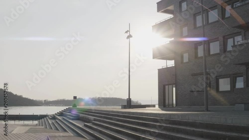 4K anamorphic video with forward motion of the Oslo fjord and a beautiful sunset appearing from behind an apartment building on Sørenga pier, a popular tourist destination in downtown Oslo. photo