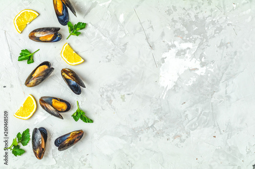 Seafood mussels, lemon and parsley on gray concrete surface