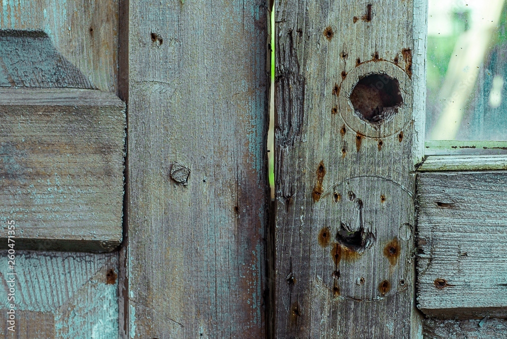 Grey wood door with holes from lock and rusty spot from nails. Horizontal grunge texture
