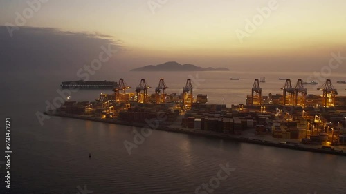 Aerial shoot of landscape with cargo terminal and city in Shenzhen,China. containers and cranes in the dock.lights on  in the eveninng, a cargo ship moving on the sea surface. photo