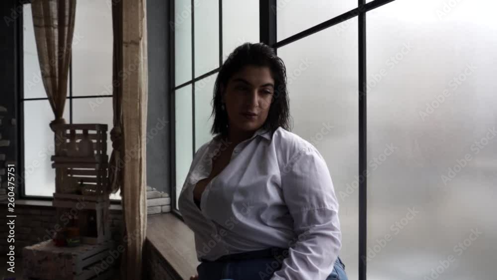 Model plus size drinks juice near the window