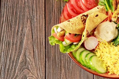 Vegetarian roll with vegetables and tofu on a large dish with rice and hummus on a wooden table close-up photo