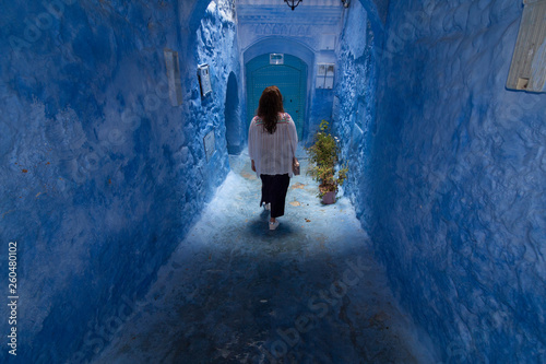 A young woman strolls through the streets of Chefchaouen, the blue town in Morocco, between the walls and the blue arches © Gustavo Muñoz
