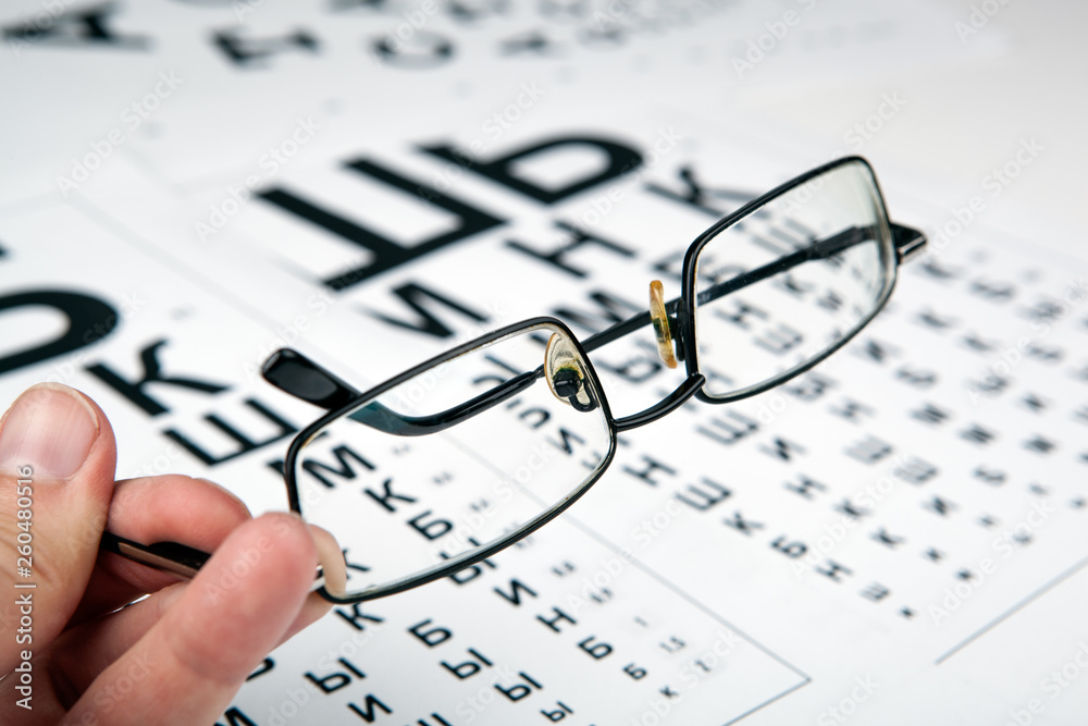 eyeglasses on the table with a font to determine of eyesight Russian version eyeglasses on the table with a font to determine of eyesight Russian version