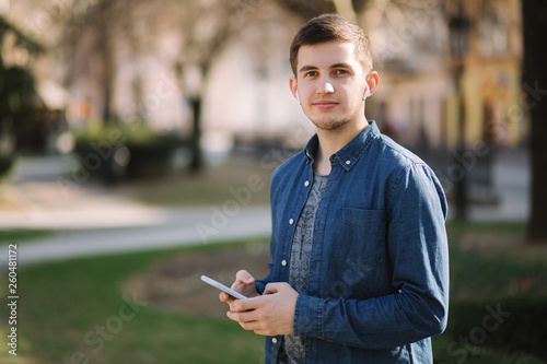 Young man use phone and wireless headphones and print message in social network