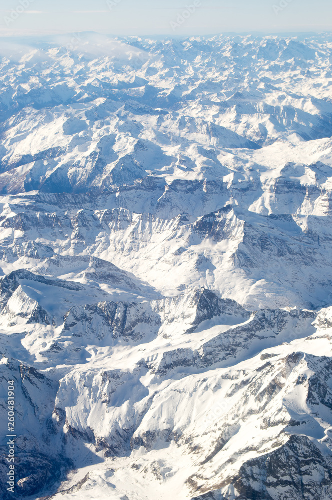 The alps mountains covered by white snow seen from the plane window