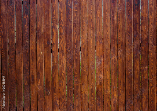 Wooden fence from rough pine oiled dark planks verticaly attached . Horizontal wood texture