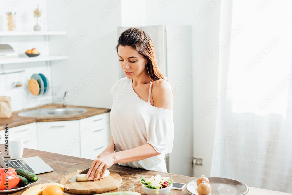 Young woman cutting bananas with knife at table in kitchen Young woman cutting bananas with knife at table in kitchen